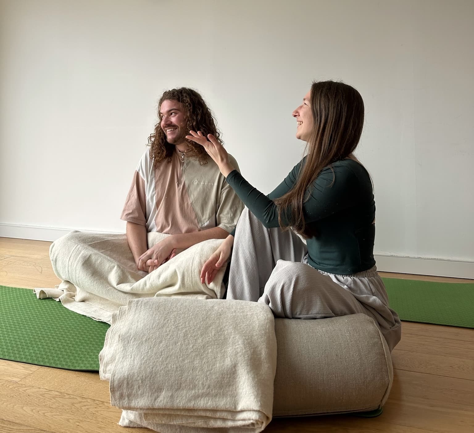 Mat and Ania sitting together on yoga mats, laughing